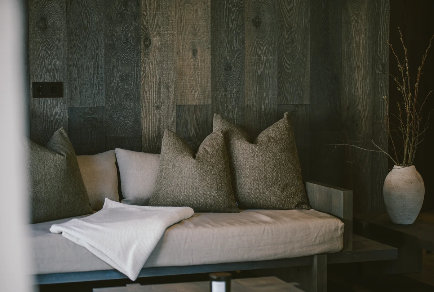 Wohnbereich-Detail einer Birgkar-Lodge, Sofa mit Kissen vor Eichenholzwand