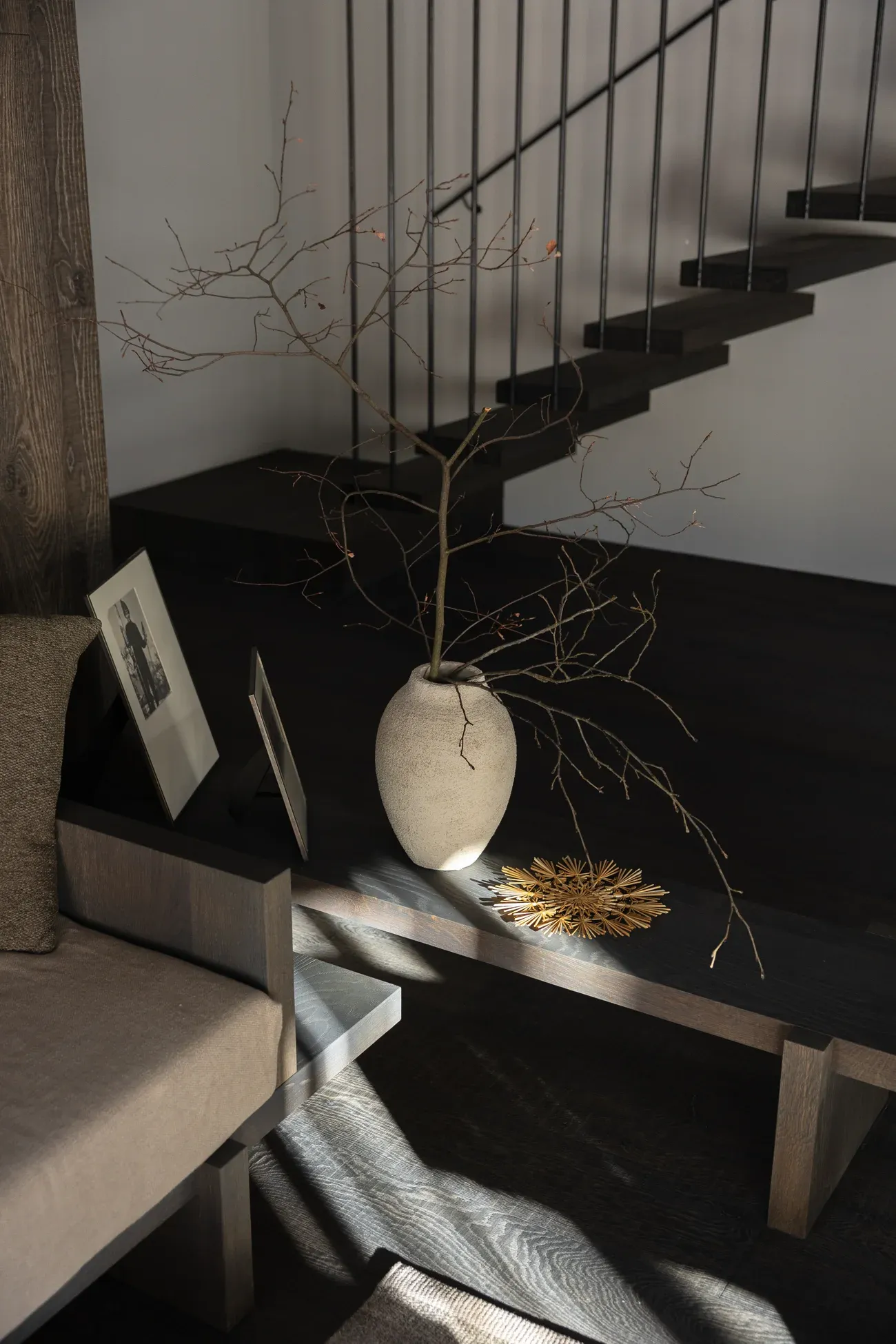 Stilvolles Wohn-Detail einer Birgkar-Lodge, Vase mit Zweigen und gerahmtes Foto in warmem Licht